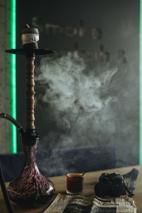 A tall hookah with smoke drifting above a table